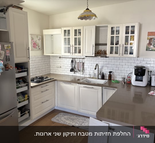 מטבח מודרני עם ארונות לבנים ומשטח עבודה